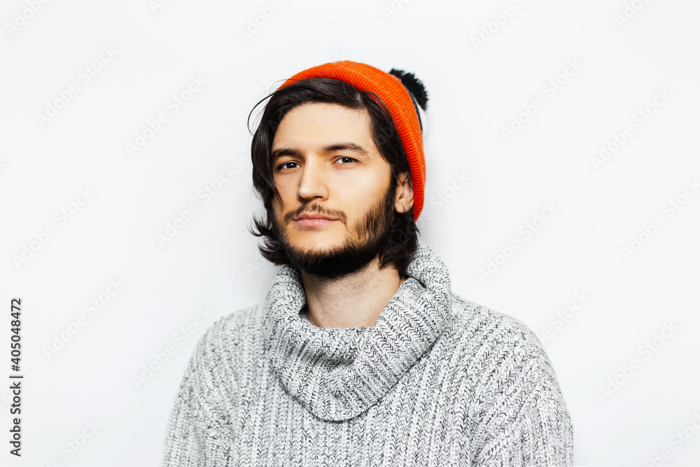 Studio portrait of young guy with orange hat and grey sweater on white background. Studio portrait of young guy with orange hat and grey sweater on white background.
