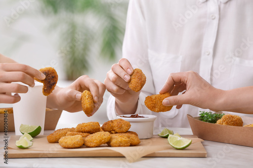 Bild auf Leinwand Women eating tasty nuggets with ketchup on table in room
