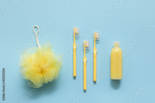 Cosmetic bottle  toothbrushes and shower sponge on color background