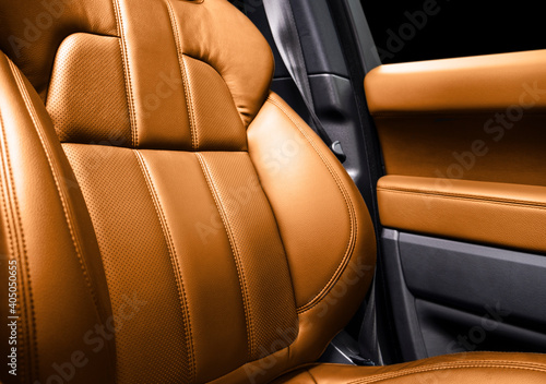 Modern luxury car brown leather interior. Part of orange perforated leather car seat details with white stitching. Interior of prestige car. Comfortable perforated leather seats. Perforated leather. © Aleksei