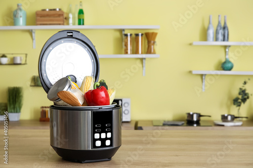 Modern multi cooker with vegetables on table in kitchen