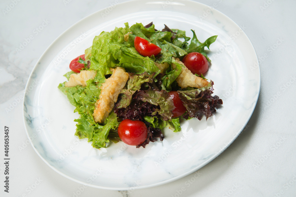 Side view of Chicken Tempura Salad served on marble plate. Meat Dish with deep fried chicken strips, lettuce and cherry tomatoes on white background. Healthy salad with chicken slices in breading
Side view of Chicken Tempura Salad served on marble plate. Meat Dish with deep fried chicken strips, lettuce and cherry tomatoes on white background. Healthy salad with chicken slices in breading
