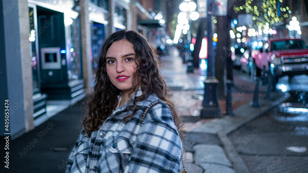 イルミネーションの輝く街中でカメラ目線でデートを楽しむラテン系の女性