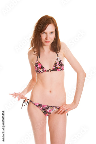 Closeup portrait of a slim brunette woman wearing a bikini, isolated in front of white studio background
