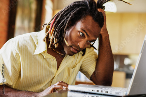 Man with hand on head while working on laptop