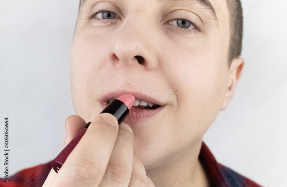 Close-up of a man painting his lips. The concept of protecting the rights of the LGBT community, a clear manifestation of homosexuality and the manifestation of female qualities in men.