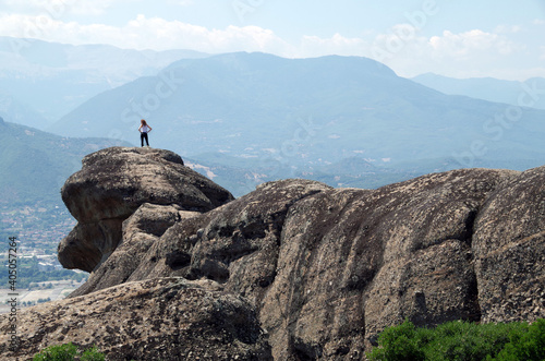 a girl stands on the edge of a cliff in Meteora Greece