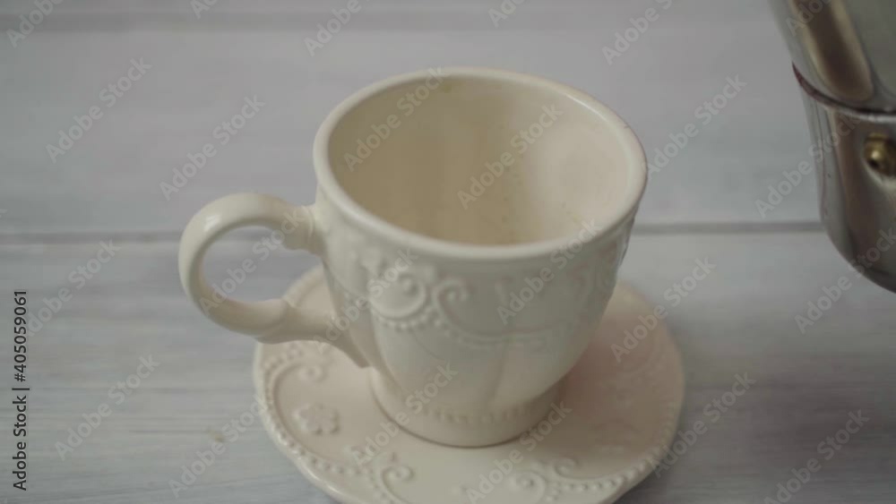 Hot coffee is poured into a cup on a white table. Slow motion Hot coffee is poured into a cup on a white table. Slow motion