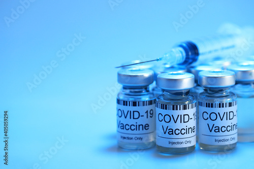 Blue filter light effect of Covid-19 vaccine injection vials medicine drug bottles and syringe. Covid-19 vaccination, immunization, treatment to cure Corona Virus infection. Soft focus image.