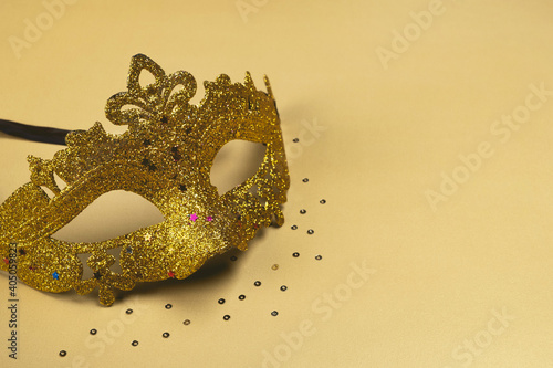 Carnival Mask with glitter on golden background. Festive party, Mardi gras or Purim holiday. Copy space, close up