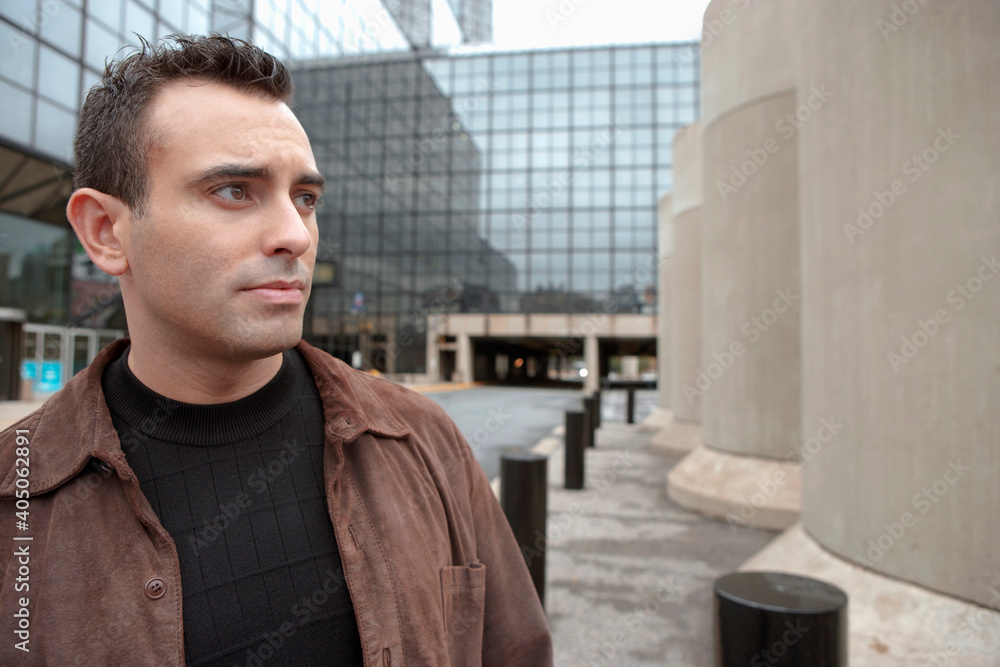 Serious Hispanic man standing in urban courtyard