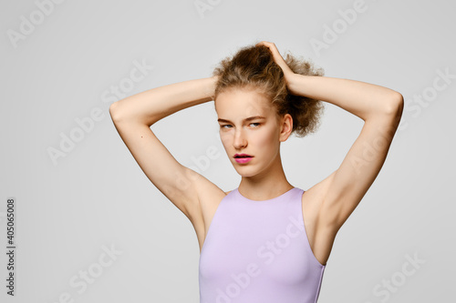 Portrait of young woman in t-shirt lifting hair with hands © boomeart