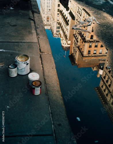 Painting buckets on pavement beside street water reflecting building near by photo