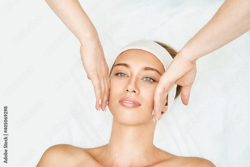 Face massage at spa salon. Doctor hands. Pretty female patient. Beauty treatment. Healthy skin procedure. Young woman head. Light background. Scrub rejuvenation. Facial dermatology mask. Detox therapy