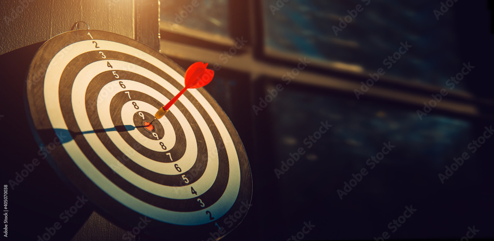 Dart arrow hit on bulleyes of dartboard to represent that the business reached the target with dark tone picture style. Target and goal as concept. Dart arrow hit on bulleyes of dartboard to represent that the business reached the target with dark tone picture style. Target and goal as concept.