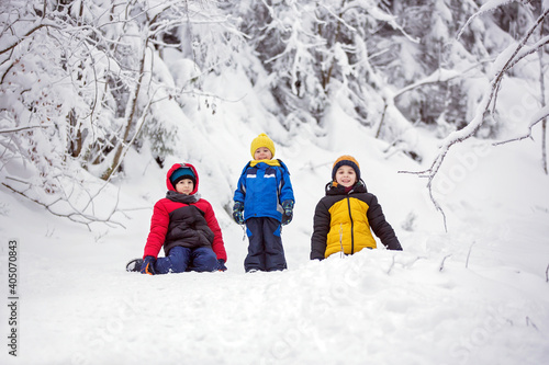 Sweet happy children, brothers, playing in deep snow in forest, frosted trees