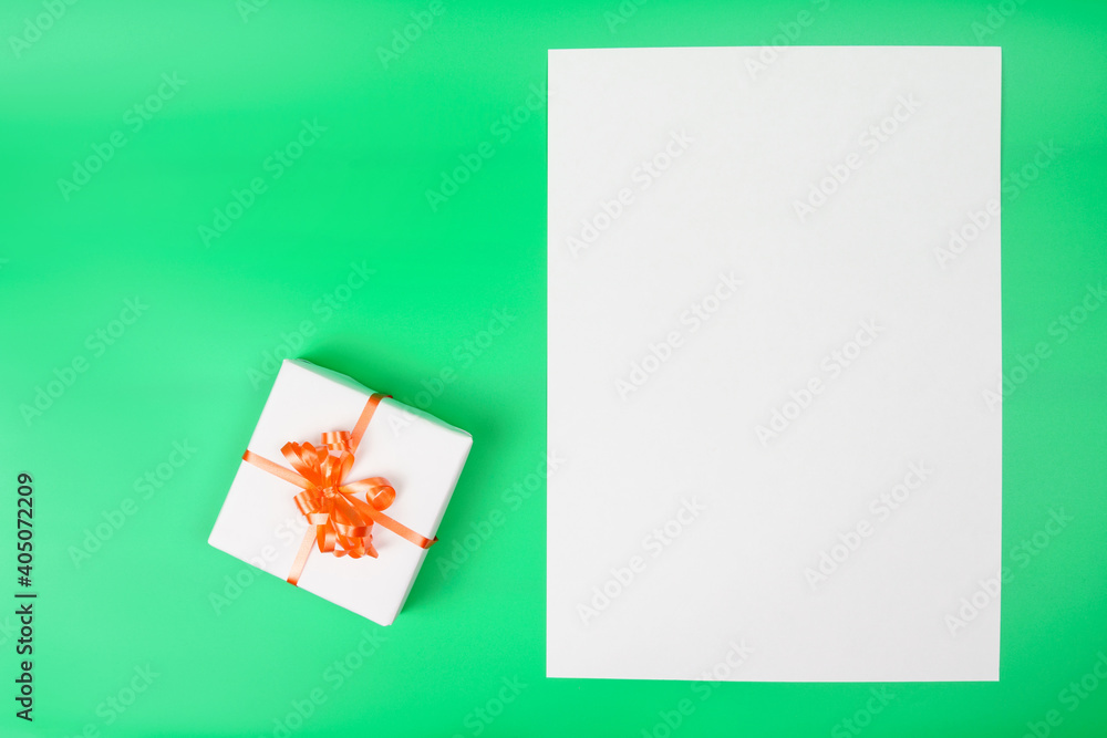 White gift box on green background and blank card for copy space. White gift box on green background and blank card for copy space.