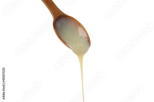 Spoon with dripping condensed milk isolated on white background