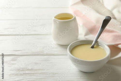 Fotografie Kitchen towel and bowls with condensed milk on wooden background