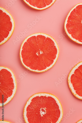 Patterns of slices of juicy grapefruit on a pink background, a beautiful pattern.