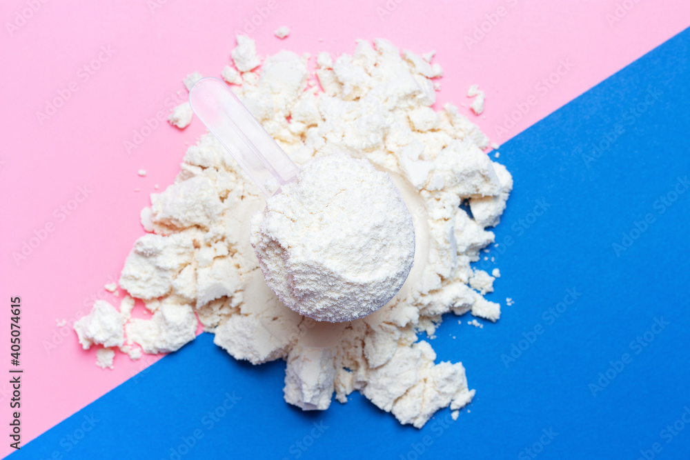 Scattered protein and scoop on blue and pink background. Scattered protein and scoop on blue and pink background.