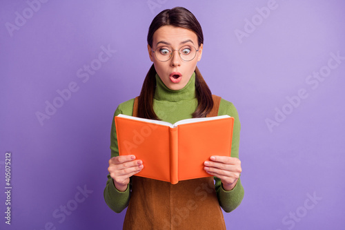 Portrait of pretty diligent focused amazed girl reading book pout lips wow isolated over pastel violet color background