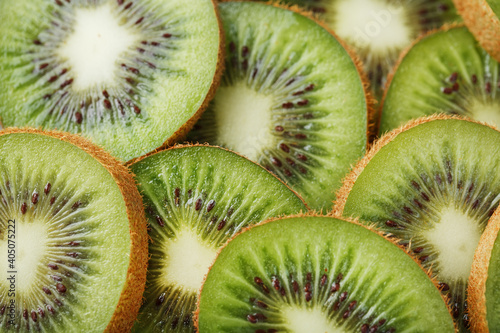 Kiwi fruit cut into slices, in full screen as a background.