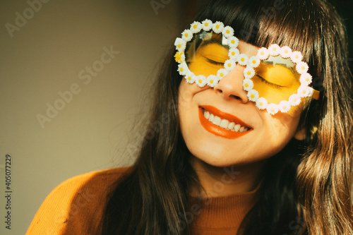 Happy, optimistic and smiling woman with flower sunglasses expresses joie de vivre and positive attitude towards life.