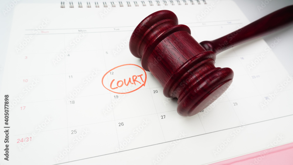 The words Court written and judge's gavel on the white calendar to remind you of an important trial date.