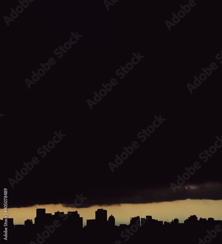 Silhouette of city buildings during sunset under huge cloud photo