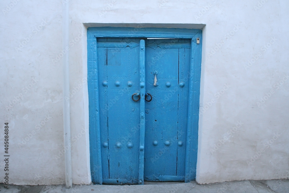Bukhara, Uzbekistan - November 27 2019: Ancient wooden door in white wall. Photo with copy space