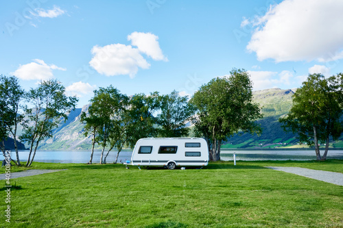 Toller Campingplatz mit Wohnwagen im Hintergrund Berge und See als Banner für Homepage