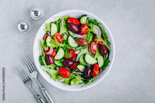 Healthy green salad with fresh tomato, cucumber, red onion, olives and lettuce in bowl