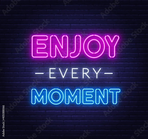 Enjoy every moment neon quote on a brick wall. Inspirational glowing lettering.