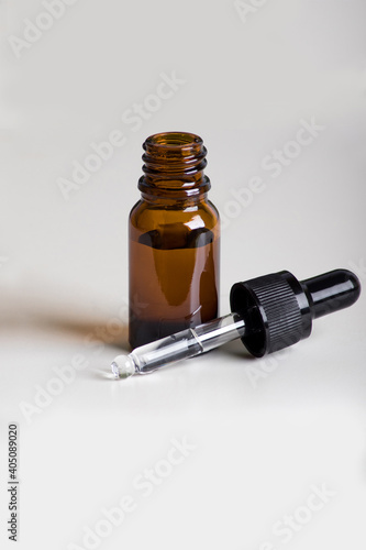 Open glass dropper on white background, detail of facial cosmetic bottle