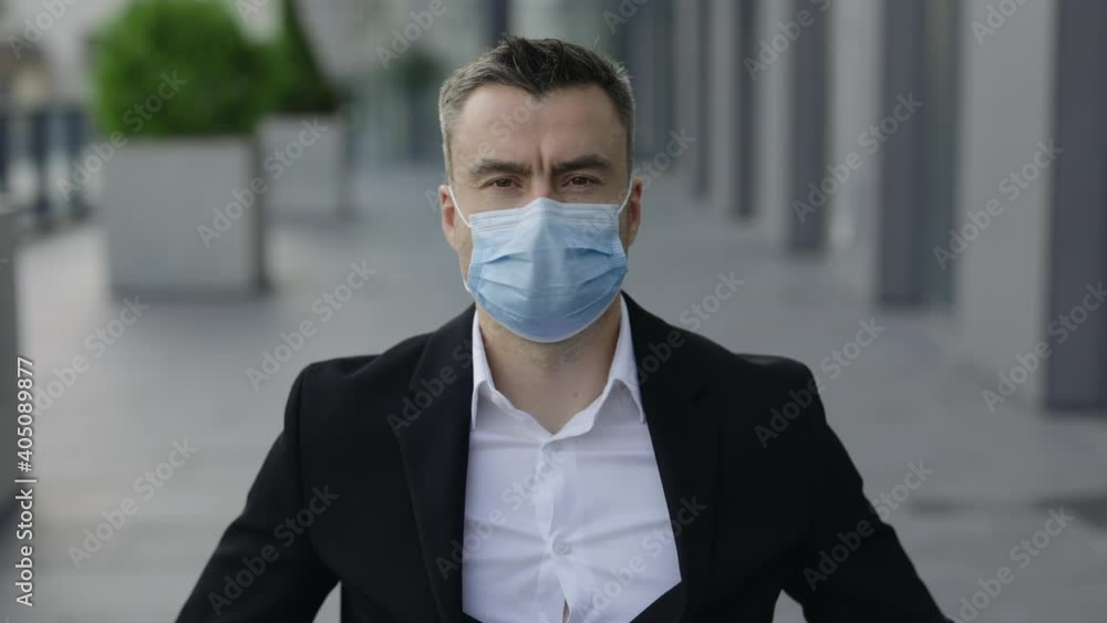 Crop view of businessman in 40s wearing medical protective mask while looking to camera. Portrait of guy in formal suit outdoors. Concept of pandemic, quarantine, healthcare. Zoom in. Crop view of businessman in 40s wearing medical protective mask while looking to camera. Portrait of guy in formal suit outdoors. Concept of pandemic, quarantine, healthcare. Zoom in.