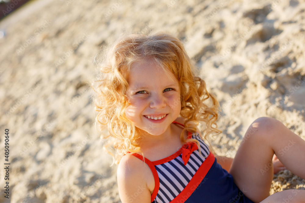 little girl sitting on the beach on the sand summer; Stock Photo