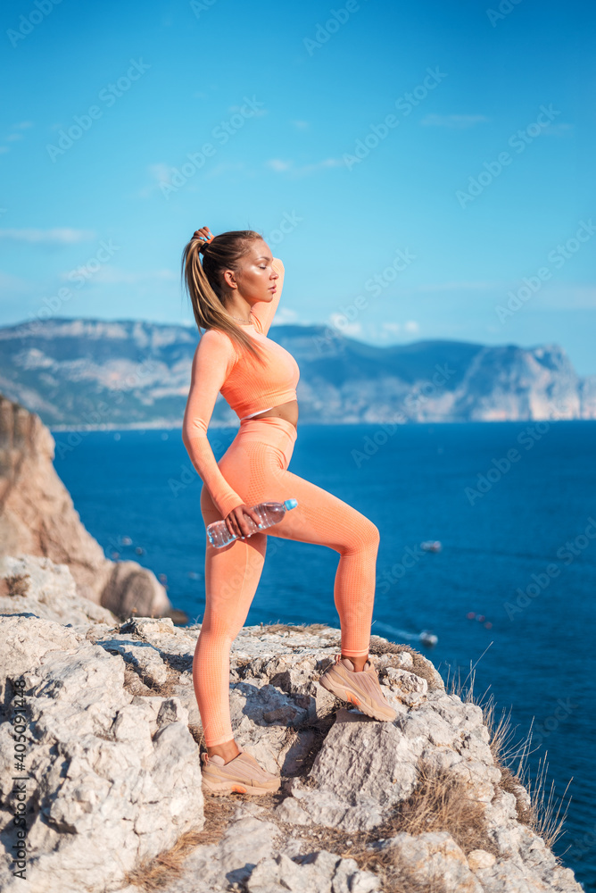 Shot of beautiful female runner standing outdoors holding water bottle. Fitness woman taking a break after running workout. Shot of beautiful female runner standing outdoors holding water bottle. Fitness woman taking a break after running workout.