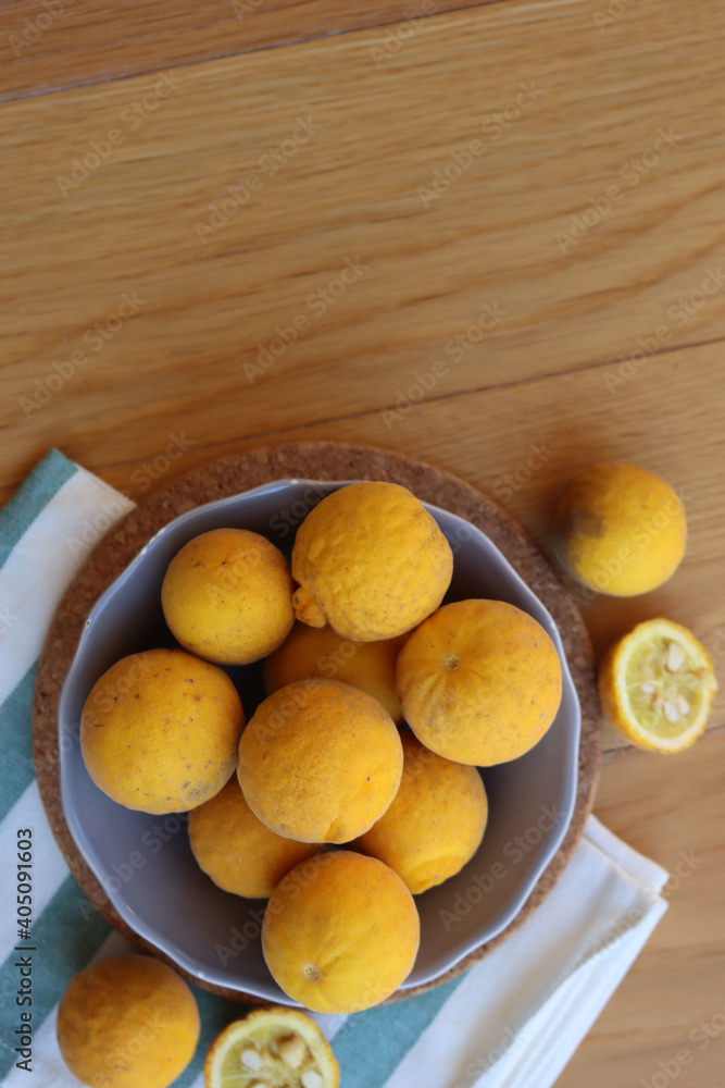 Trifoliate yellow fruits on wooden table. Many Poncirus trifoliata fruits in a bowl Trifoliate yellow fruits on wooden table. Many Poncirus trifoliata fruits in a bowl