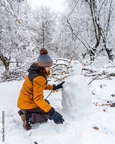 A young woman making a snowman in the snowy forest of the Artikutza natural park in oiartzun near San Sebastián, Gipuzkoa, Basque Country. Spain