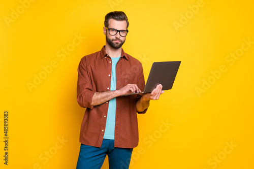 Photo of young serious focused minded handsome man businessman boss working in laptop isolated on yellow color background