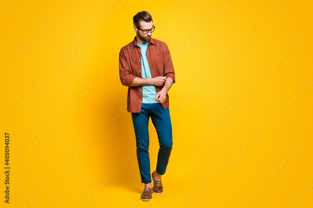 Fototapeta premium Full length body size photo of stylish millennial fixing sleeve wearing spectacles isolated on bright yellow color background