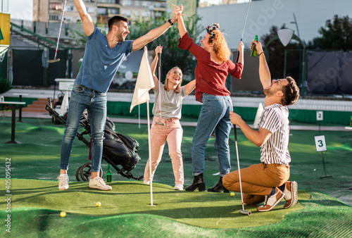 Group of smiling friends enjoying together playing mini golf in the city. © Zoran Zeremski