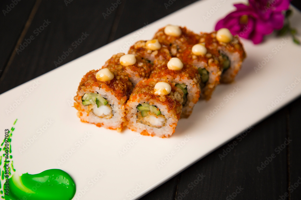 Top view of Japanese sushi roll with tempura black tiger shrimp, cucumber served with sauce. Purple flower blossom and green painting brush stroke decoration on white plate, Black Wooden background
Top view of Japanese sushi roll with tempura black tiger shrimp, cucumber served with sauce. Purple flower blossom and green painting brush stroke decoration on white plate, Black Wooden background