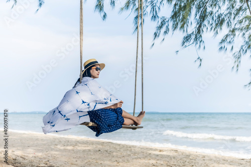 Adult Asian woman sitting on the beach swing