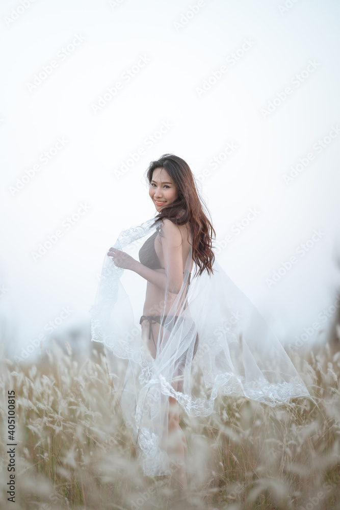 Beautiful blonde women in a brown bikini on a brown meadow with white flowers in the summer evenings.