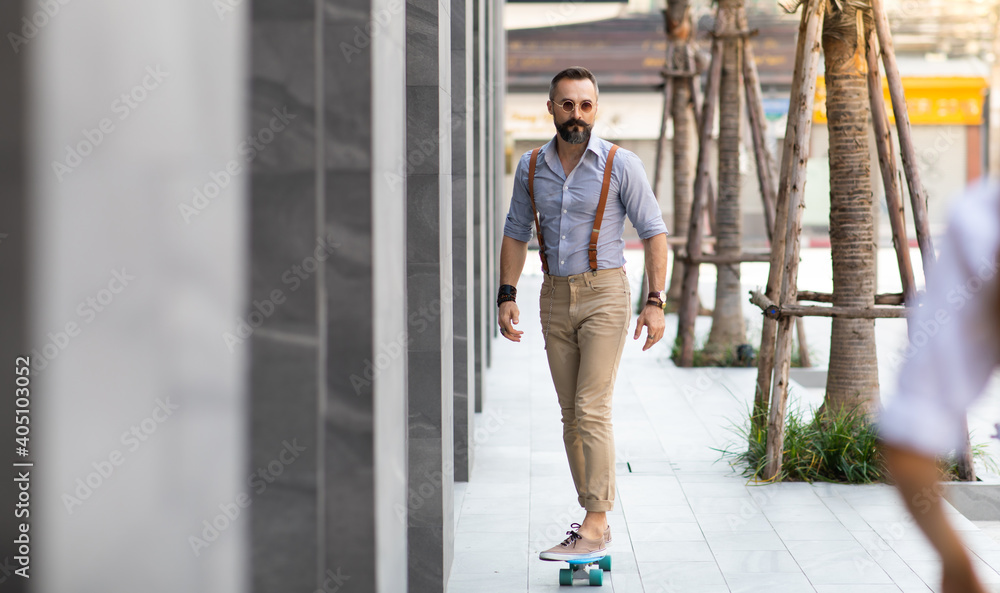 Stylish hipster bearded man skater riding a longboard on street at the city.