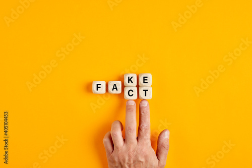 Male hand pushing the wooden cubes and transforming the word fake to fact
