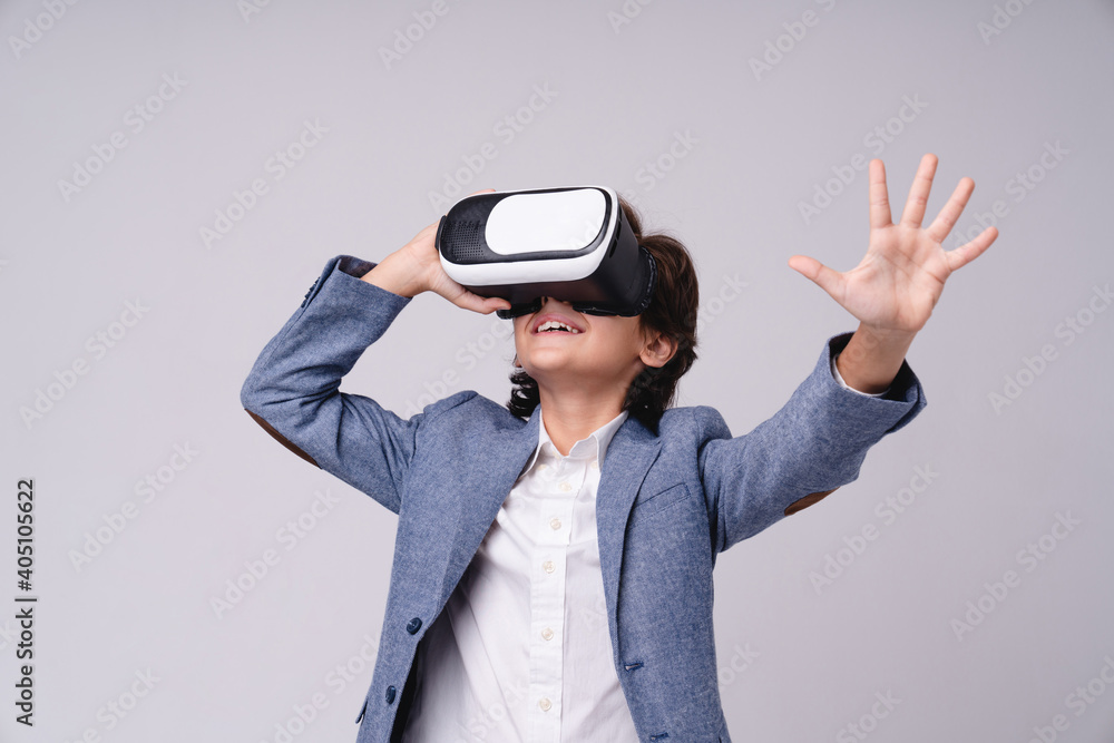 Young 10s boy in formal outfit using VR glasses isolated over grey background Young 10s boy in formal outfit using VR glasses isolated over grey background