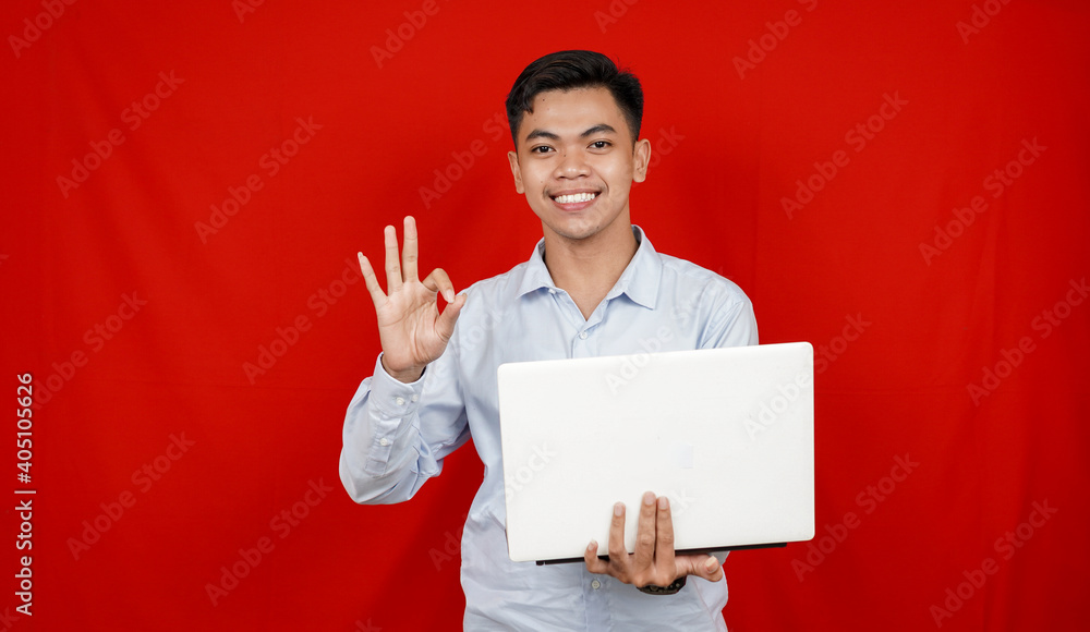 Asian business man OK geesture and laptop on table isolated red background Asian business man OK geesture and laptop on table isolated red background
